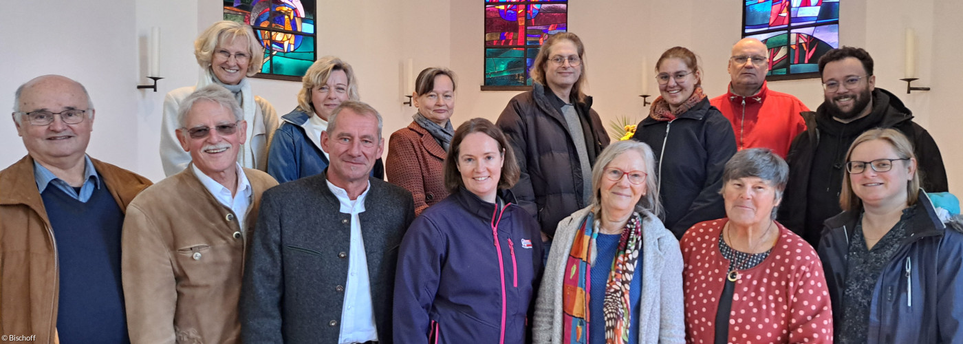 Die 14 Personen des erweiterten Kirchenvorstands fotografiert vor den bunten Fenstern der Dreifaltigkeitskirche.