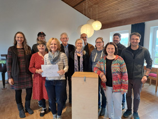 Elf fleißige Personen haben die Kirchenvorstandswahl 2024 organisiert und betreut. Auf dem Bild stehn sie hinter der Wahlurne.