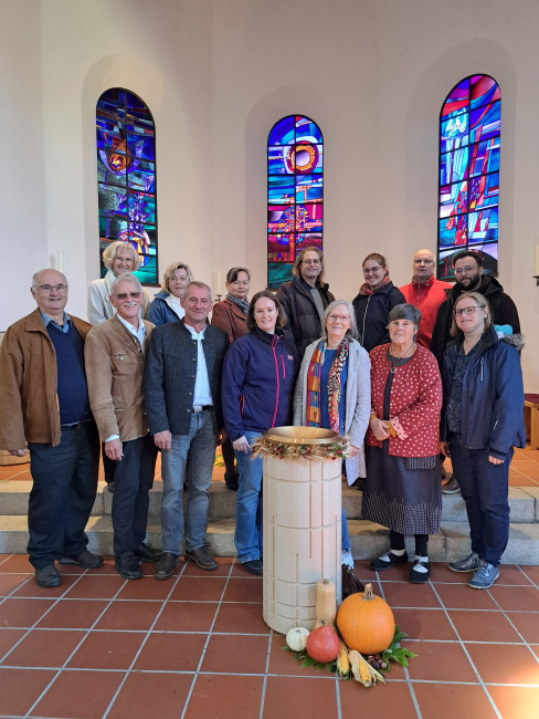 Die vierzehn Personen des erweiterten Kirchenvorstands stehen in der Dreifaltigkeitskirche vor dem Taufstein.